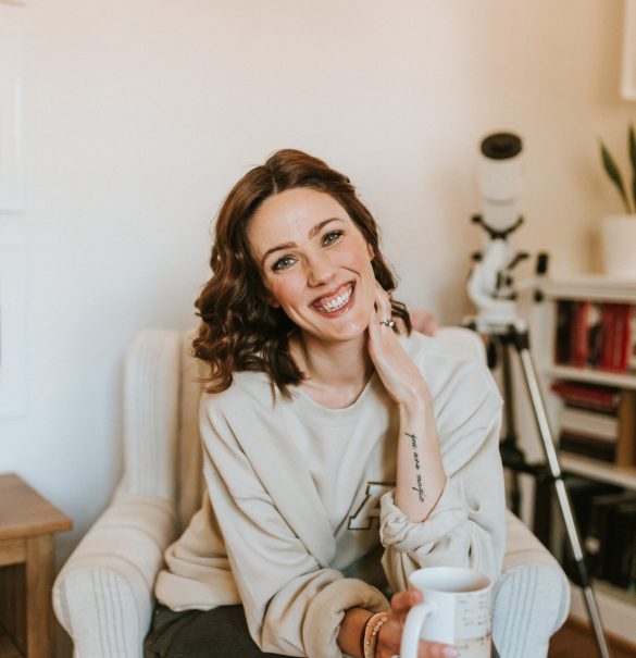 Woman sitting in a chair holding coffee and smiling