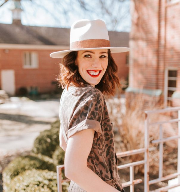 Woman wearing a hat and red lipstick smiling at the camera