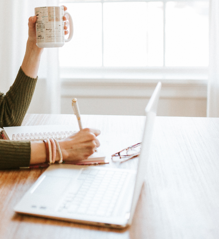 Female entrepreneur's hands holding pen and coffee working