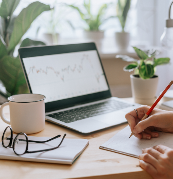 Woman holding pencil with laptop and coffee